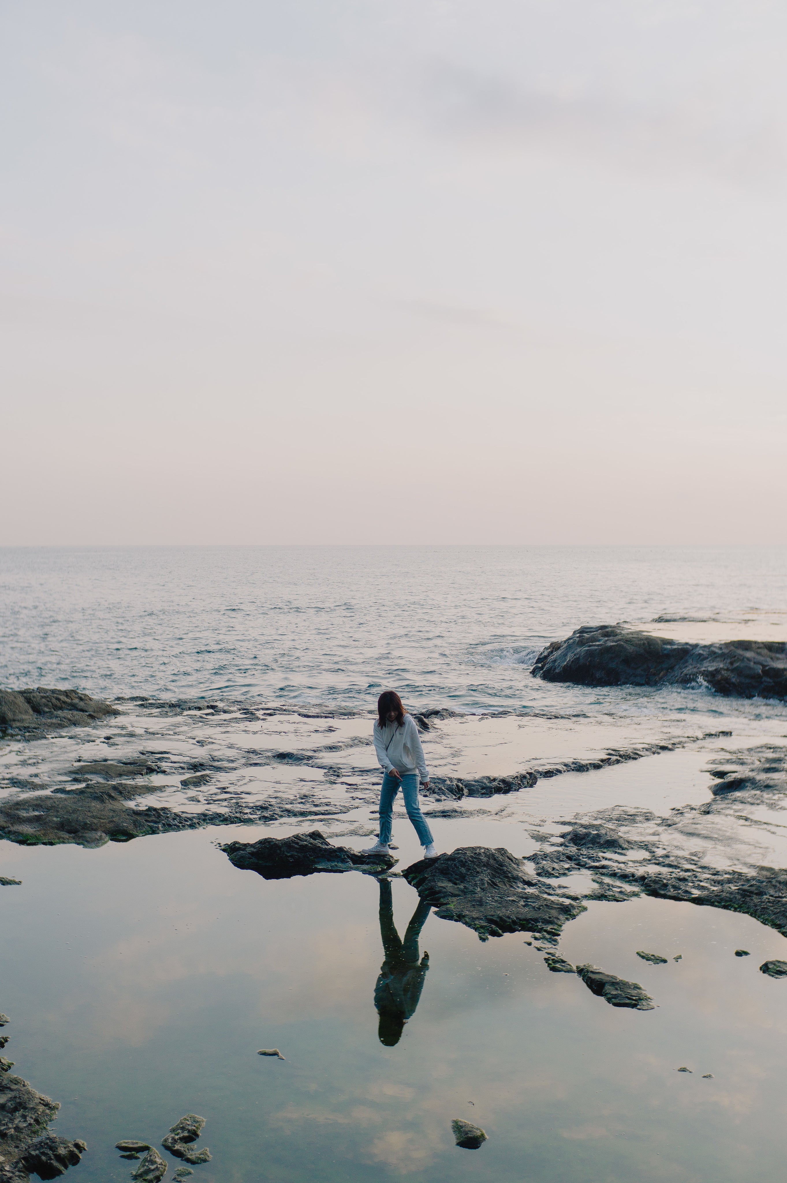 person-stands-on-rocks-poking-out-of-the-ocean-shoreline.jpg